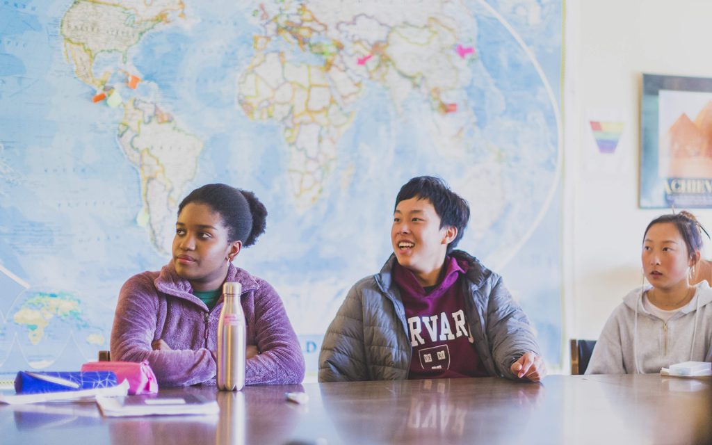 Students in a classroom with a world map behind them